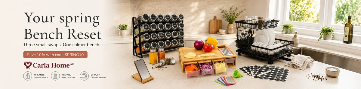 Promotional banner for Carla Home 'Your Spring Bench Reset' featuring a kitchen scene with a black rolling spice rack, a wooden cutting board, a dish drainer, and various kitchen items on a light beige countertop.