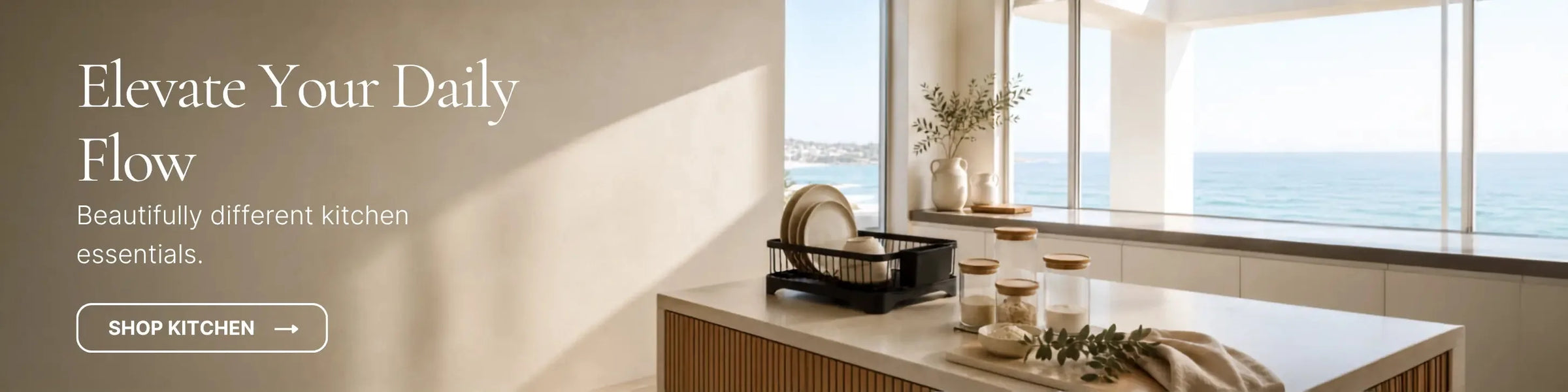 Modern coastal kitchen bench featuring a black dish drying rack, glass storage canisters, and an ocean view.